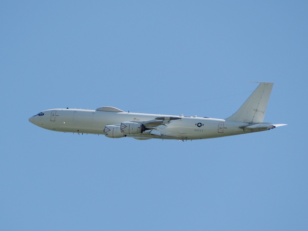 A large grey aircraft with four engines flying over a base.
