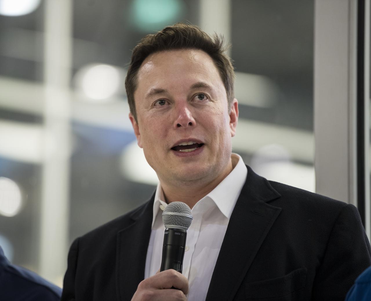 Elon Musk speaks in front of a Crew Dragon spacecraft.