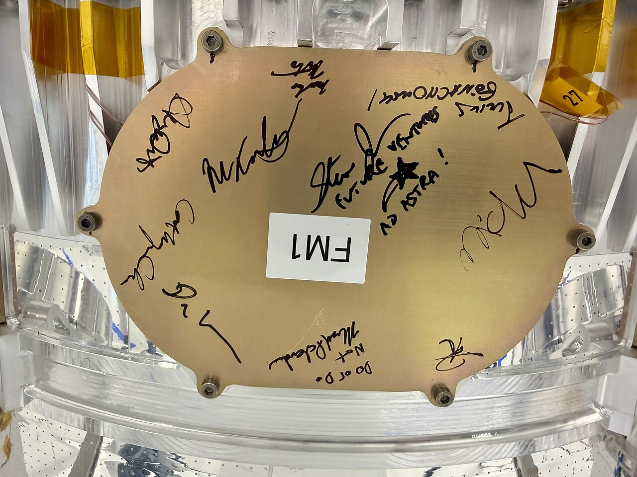 A person signs a white satellite with solar panels.