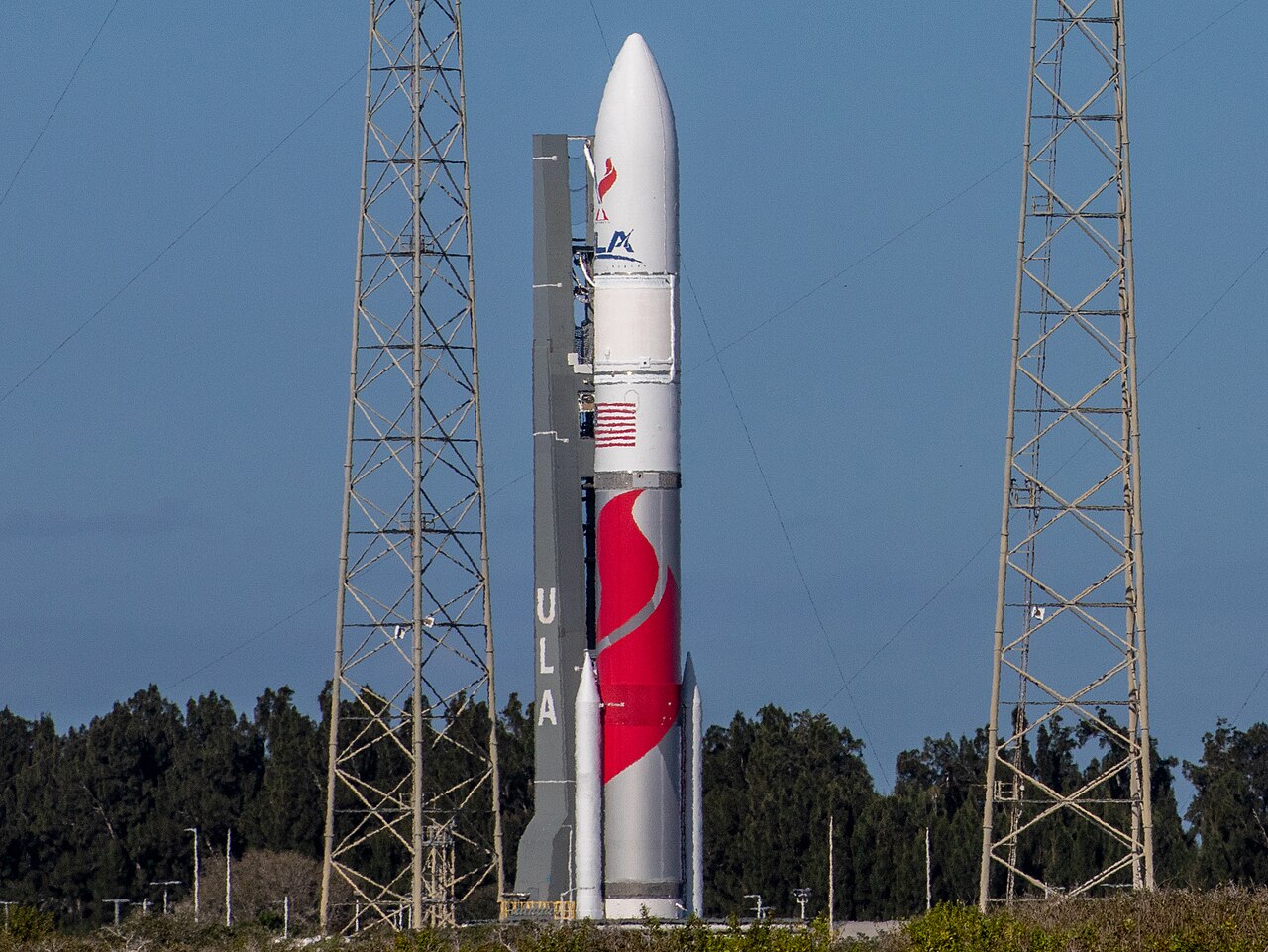 A large white rocket on a launch pad, with a mobile service tower next to it.